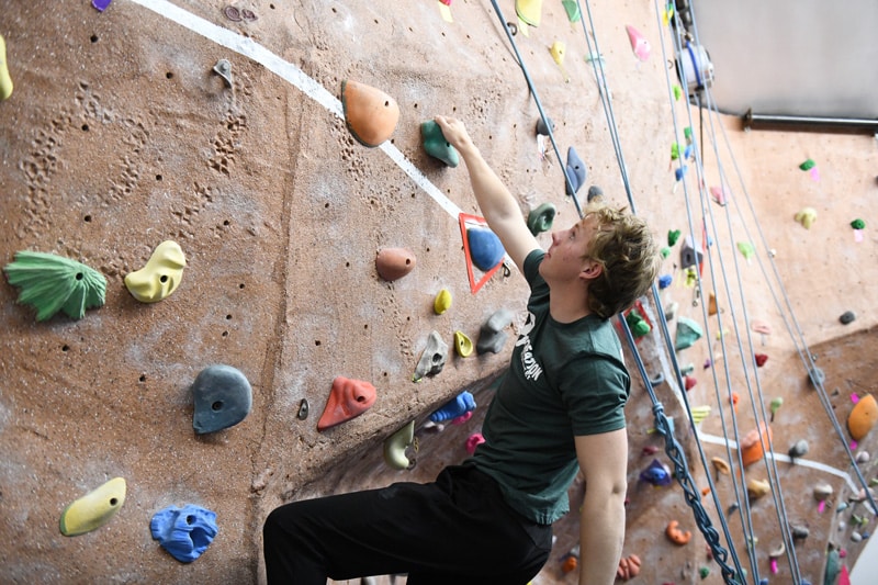 young male climbing the wall without a rope